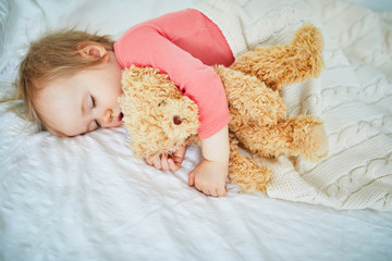 Adorable baby girl sleeping with her favorite toy