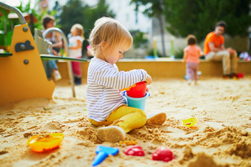 Adorable little girl on playground in sandpit