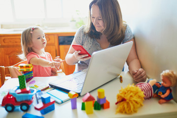 Exhausted and stressed mother working from home with toddler