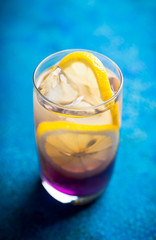 Gin based colorful cocktail with lemon and lavender liqueur on the rustic background. Selective focus. Shallow depth of field.
