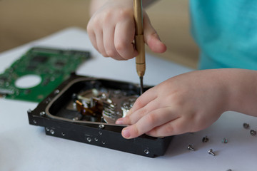 Naklejka premium An inquisitive child is experimenting with a broken hard drive