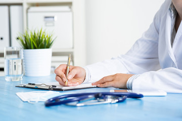 Close-up of female doctor filling medical form