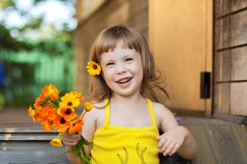 Little girl sitting in a summer cottage with a bouquet of yellow flowers