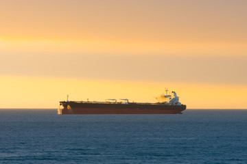 Obraz premium Cargo ship at sunset in the coasts of Chile outside the port of Valparaiso.