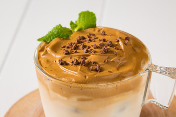 Whipped dalgona coffee with 
spearmint on a white wood background,   copy space