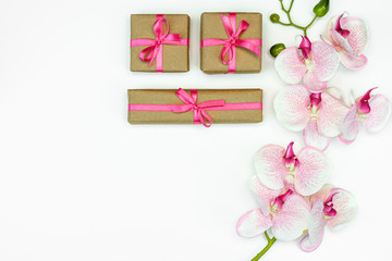 flatlay of Gift present boxes with pink ribbon, orchid flowers on white background. spring concept. Copy space