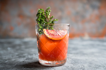 Old-fashioned cocktail with blood oranges and thyme on the rustic background. Selective focus. Shallow depth of field.
