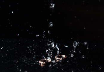 Obraz na płótnie Canvas wedding rings with the water splash on black background