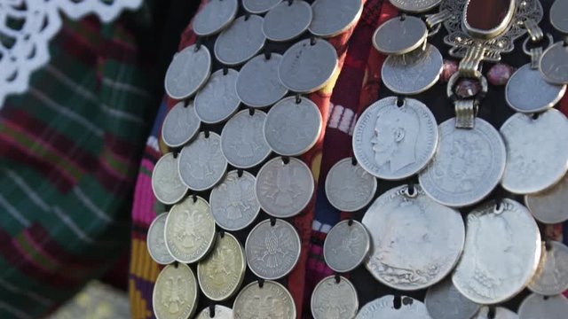 Close up shot of Folklore monist necklace of national Finno Ugric clothes. Ensemble indigenous woman dancing around in traditional clothing outdoor.