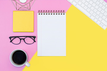 pink and yellow working place layout. note pad. writing. coffee, keyboard, glasses. spring concept. copy space flat lay