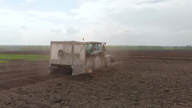 Rapeseed sowing tractor seeder selection field spring. In the background, wheat plots.