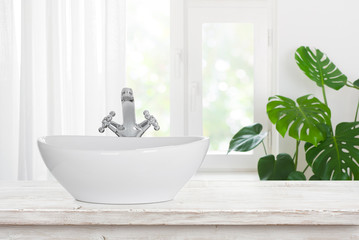Modern wash basin with shiny faucet on vintage bathroom table