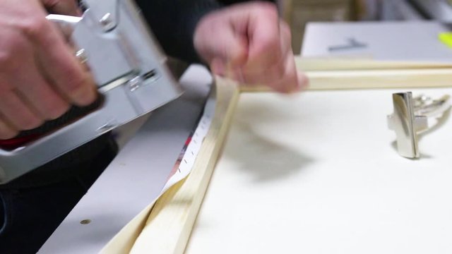 Canvas stretching. Wooden stretcher bar, staple gun, canvas pliers, male hands