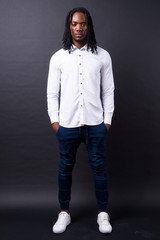 Full body shot of young handsome African businessman with dreadlocks