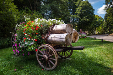 Fototapeta na wymiar Flowering village in Alsace. Cart with logs decorated with flowers.