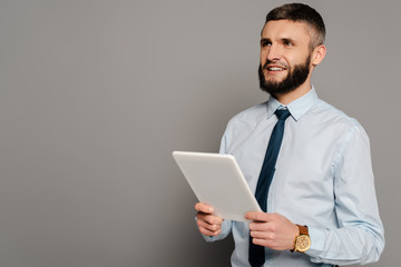 smiling handsome bearded businessman with digital tablet on grey background