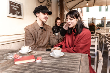 Blurred foreground of two lovers in the bar. In the background a beautiful sad girl with smartphone. Concept of abandonment VS happiness.