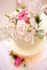 Obraz na płótnie Canvas Bright creamy cake decorated with fresh flowers on white background