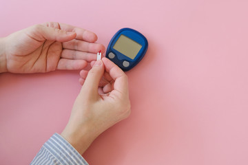 Female hands holding test strip for blood glucose measurement using glucometer. Diabetes, gestational diabetes mellitus concept.