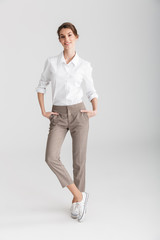 Image of young cheerful woman smiling and posing with hands in pockets
