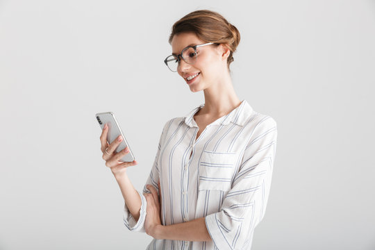 Image of joyful beautiful woman in eyeglasses typing on mobile phone