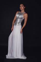 Pretty girl posing in a fashion dress over black background