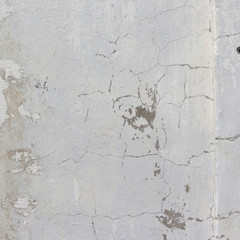 the white wall of an old house with beautiful cracks from time. white paint and whitewash on the wall. the background is white with soft blue and yellow. white old wall background