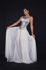 Fototapeta premium Pretty girl posing in a fashion dress over black background