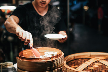 Asian Culture Street food booth selling Chinese specialty Steamed Dumplings preparation cooking in a bamboo basket at restaurant Chinese food.Assortment of different types of asian traditional.