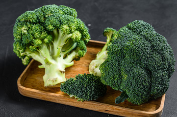 Fresh broccoli in a wooden bowl. Black background. Top view.