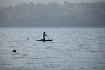 A person practicing paddle surf on the beach at sunrise Backlight.Silhouettes of people practicing surfing.