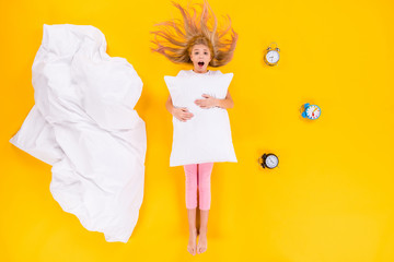 Top view above high angle flat lay flatlay lie concept of her she little small healthy girl holding pillow childish clock wakeup oversleep isolated bright vivid shine vibrant yellow color background