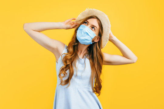 a girl in a hat in summer, wears a medical protective mask against a viral infection, on a yellow isolated background. Quarantine, coronavirus, summer