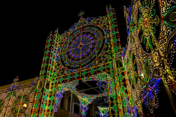Obraz premium Beautiful multi colored illuminated street decoration for La Festa di San Rocco, Saint Roch's Feast in Montescaglioso, Province of Matera, Basilicata Region, Italy at night