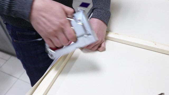Canvas stretching. Wooden stretcher bar, staple gun, canvas pliers, male hands