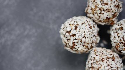 Healthy raw energy balls with cocoa, coconut, sesame, chia on grey background.