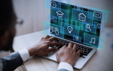 African American businessman working on his laptop in office, selecting functional icon from virtual interface, collage