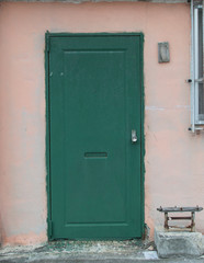 ラフに緑の塗装をした鉄の扉
