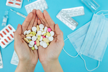 The doctor's hands are holding pills. cure for coronavirus. Medical remedies in the fight against covid-19. Pills, syringes, thermometer, medical mask on blue table. conceptual medical background.