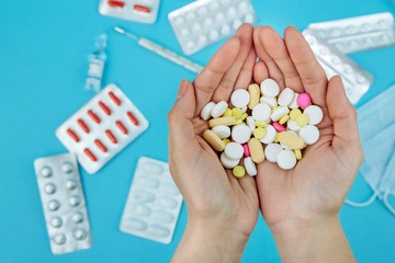 The doctor's hands are holding pills. cure for coronavirus. Medical remedies in the fight against covid-19. Pills, syringes, thermometer, medical mask on blue table. conceptual medical background.