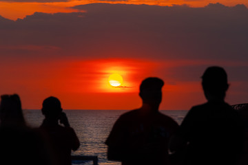 an observation deck overlooking the Indian ocean at sunset, with blurred silhouettes of people having fun on a summer evening and enjoying the sunset