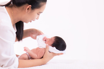 Obraz na płótnie Canvas Close up beautiful young Asian mother kissing and hold tiny adorable newborn baby girl 0-1 month on white bed with caring and love, lifestyle health care newborn at home concept on white background