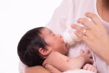 Obraz na płótnie Canvas Beautiful Asian mother hold newborn 0-1 month baby infant on her breast feeding milk by bottle, adorable baby look to her mother safety and comfortable, mother nurturing at home, motherhood task