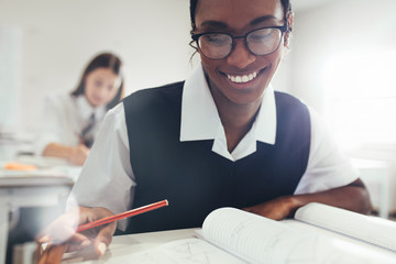 Female student smiling while studying in classroom