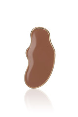 Subject shot of an irregular shaped earring with brown jeweller's enamel in the golden border. The art earring is reflected in the white surface.