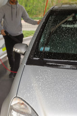 Self-service car wash. A man in a car wash washes his car.