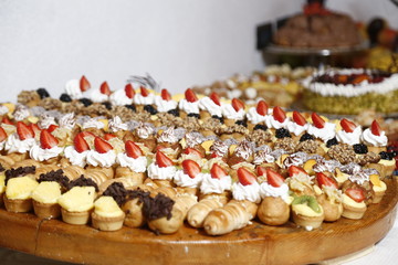 buffet with sweets. fruits and other sweets on dessert table. Rows of tasty looking desserts in beautiful arrangements. Sweets on banquet table - picture taken during catering event