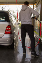 Self-service car wash. A man in a car wash washes his car.