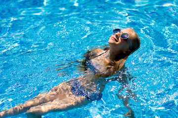 girl swims in the pool under the sun