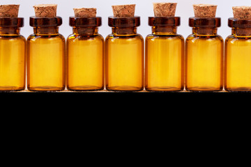 Amber-colored pharmaceutical vials with cork. Close-up. Black background for lettering or design.